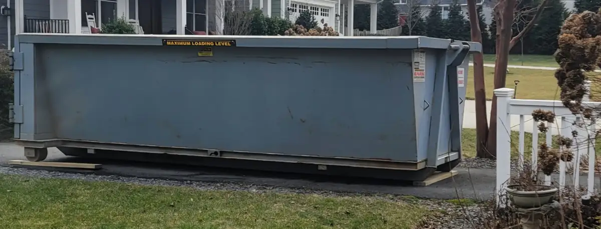 Roll off container set on boards at the edge of a driveway in Bethesda, MD