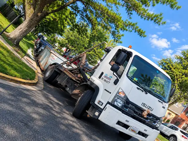 Roll Off On The Go truck on a tree-lined street in Gaithersburg, MD