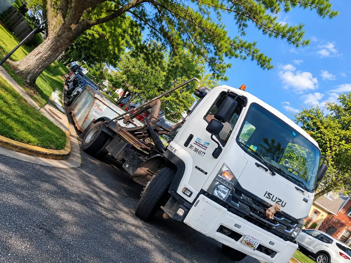 Roll Off On The Go truck on a tree-lined street in Gaithersburg, MD