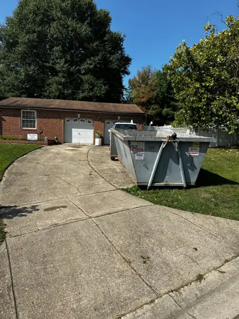 Roll off container on a curved concrete driveway in front of a brick home in Germantown, MD