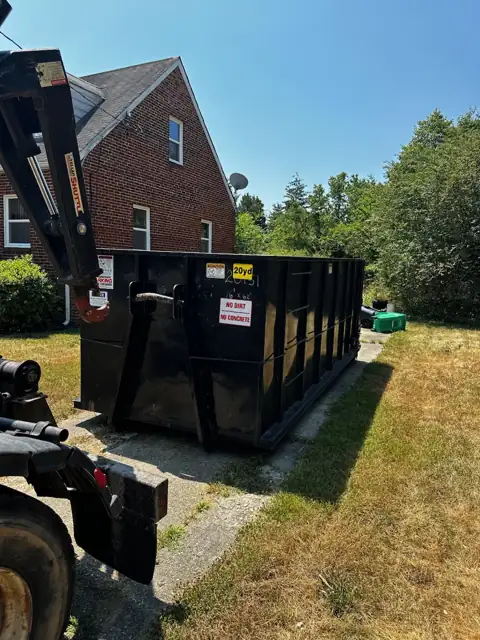Truck setting down a 20 yard roll off container beside a brick house in Germantown, MD