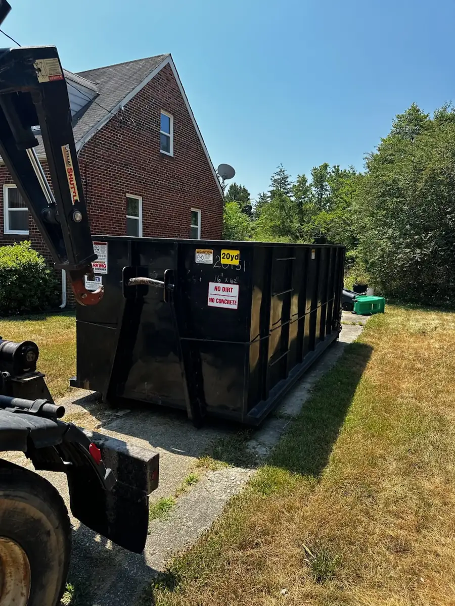 Truck setting down a 20 yard roll off container beside a brick house in Germantown, MD