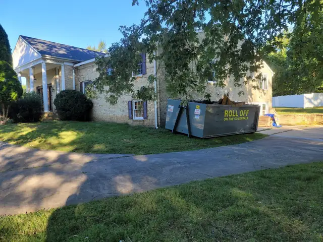 Loaded Roll Off On The Go container on the driveway of a large brick home in Potomac, MD