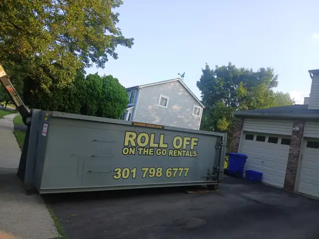 Branded Roll Off On The Go container on a driveway next to a two car garage in Potomac, MD