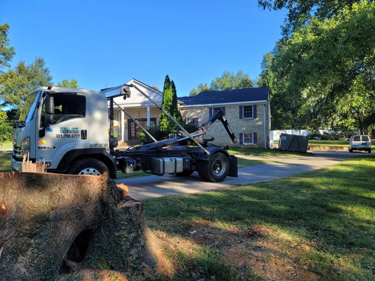 Roll Off On The Go truck in the driveway of a Potomac, MD home, with a container by the house