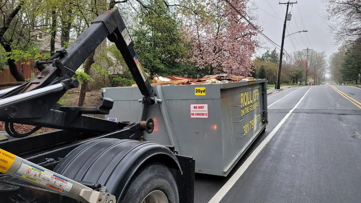 Roll Off On The Go truck hauling a loaded 20 yard container on a street in Rockville, MD
