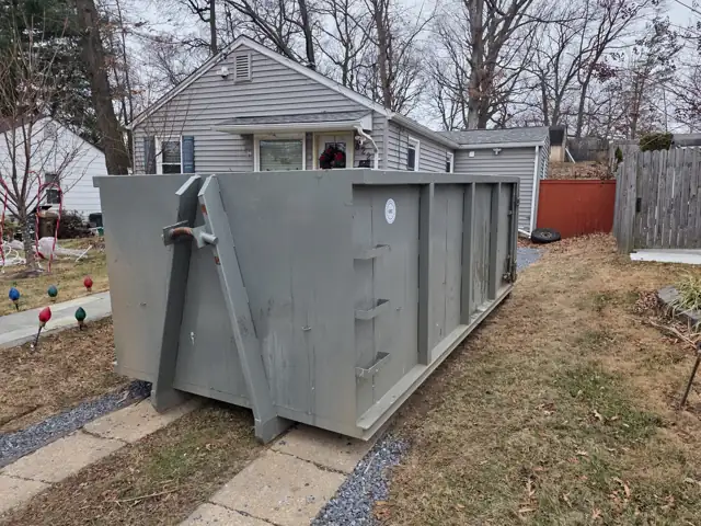 Roll off container set beside the front walkway of a small house in Rockville, MD