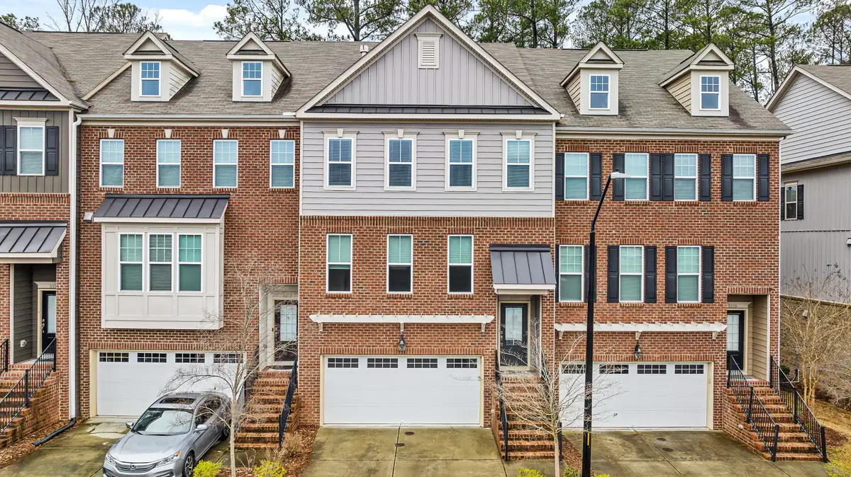 Brick and siding townhomes with garages below and front steps, with a car in one driveway